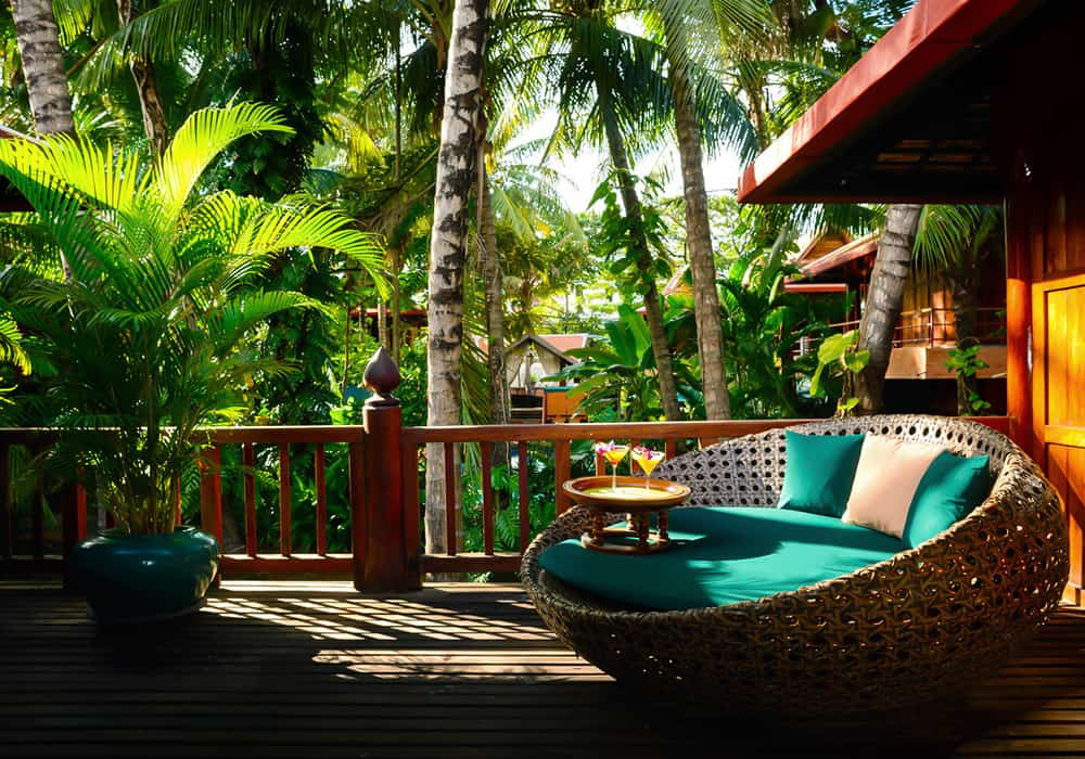 Wicker daybed on a teak terrace overlooking the gardens