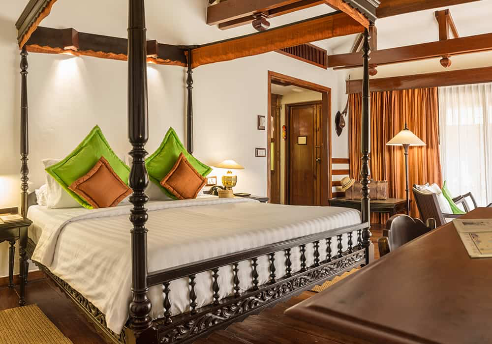 Four-poster bed with carved teak frame in a Khmer-style room