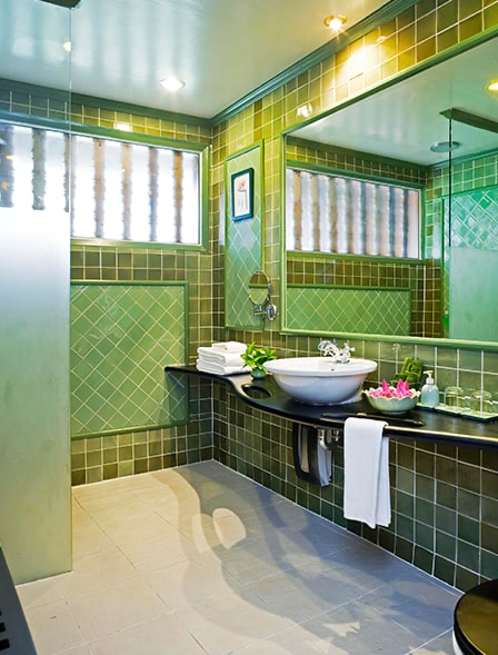 Green-tiled bathroom with rain shower and stone basin